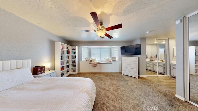 carpeted bedroom with ceiling fan, ensuite bathroom, and a textured ceiling