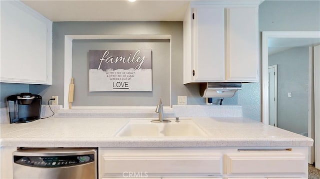 kitchen with a sink, stainless steel dishwasher, light countertops, and white cabinetry