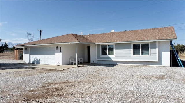 ranch-style home with a garage, roof with shingles, and driveway