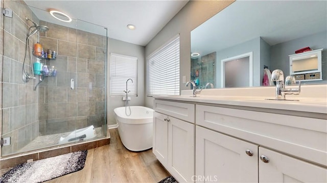 bathroom featuring vanity, a shower stall, a freestanding tub, and wood finished floors