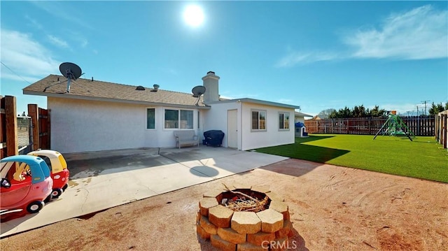 back of house with stucco siding, a fenced backyard, a playground, a yard, and a patio area