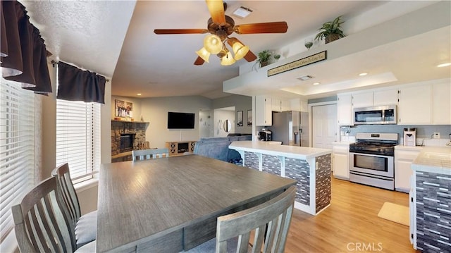 kitchen with visible vents, light wood-style flooring, wine cooler, appliances with stainless steel finishes, and light countertops