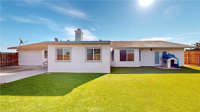 rear view of house featuring a patio, a yard, fence, and stucco siding