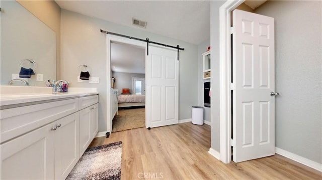 bathroom featuring visible vents, vanity, baseboards, and wood finished floors