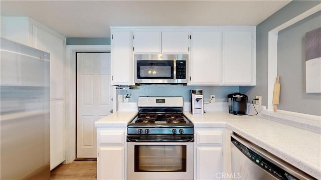 kitchen featuring light wood finished floors, white cabinets, appliances with stainless steel finishes, and light countertops