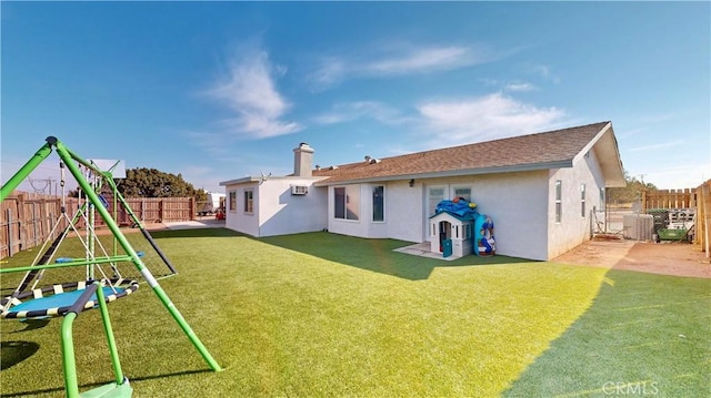 rear view of property with a fenced backyard, stucco siding, a playground, and a yard