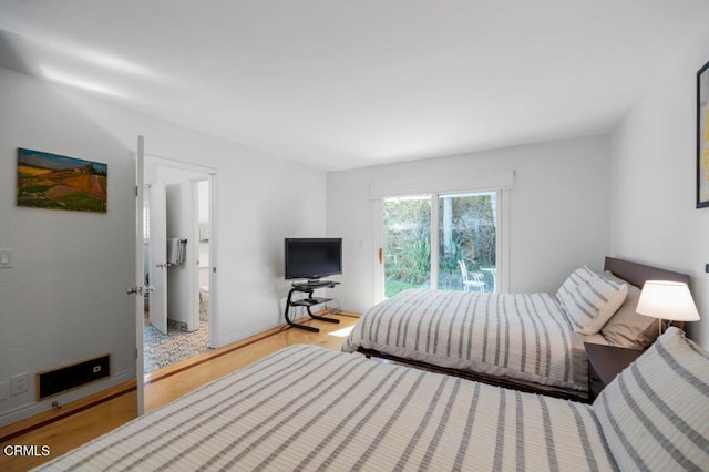 bedroom featuring access to outside, ensuite bath, baseboards, and wood finished floors