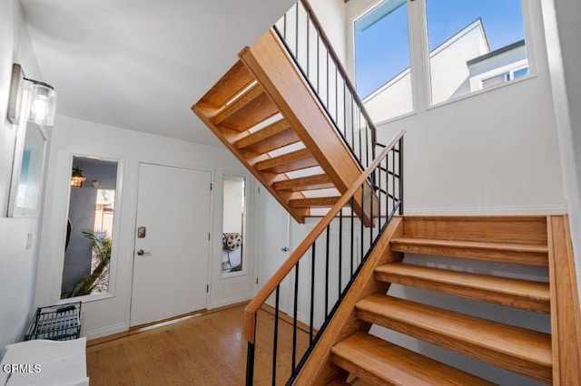 foyer with stairway, wood finished floors, and a healthy amount of sunlight