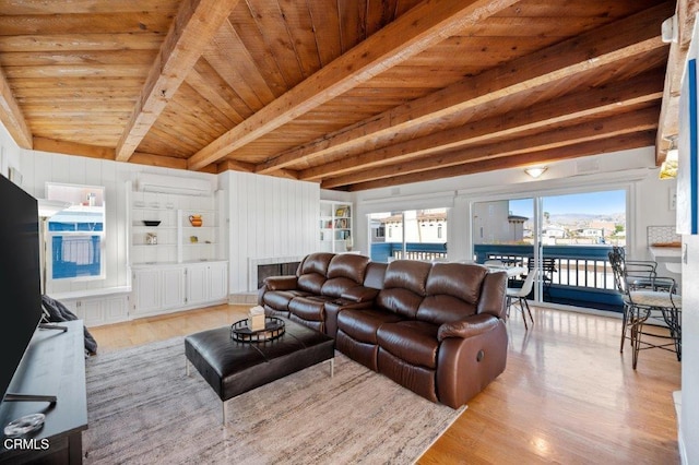 living room with beamed ceiling, light wood-style floors, an AC wall unit, and wooden ceiling