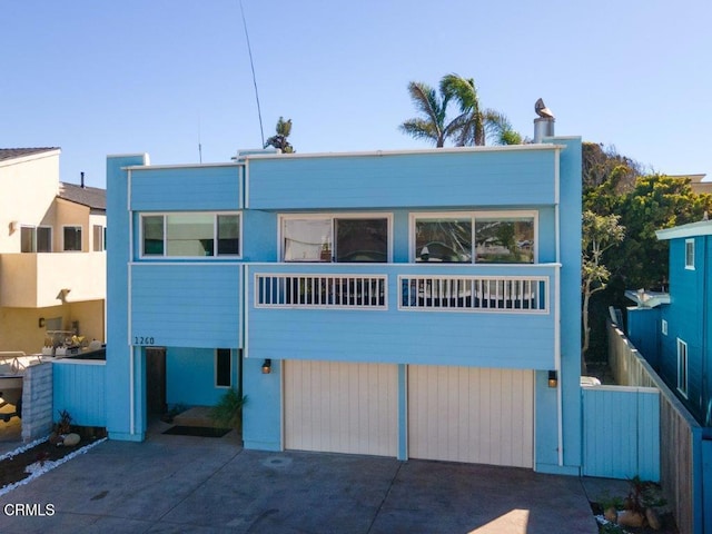 view of front of property featuring concrete driveway, a garage, and fence