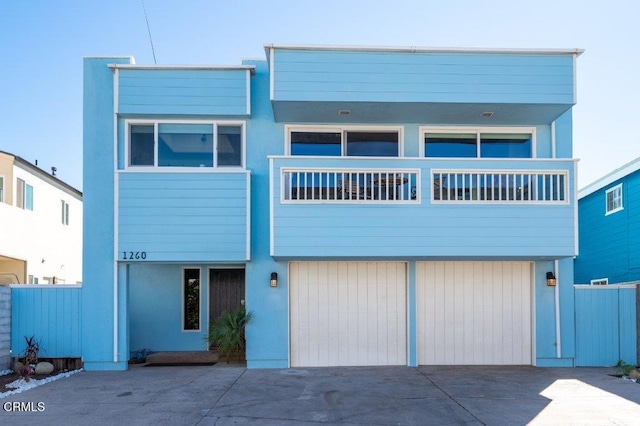 view of front of property with stucco siding, an attached garage, driveway, and fence