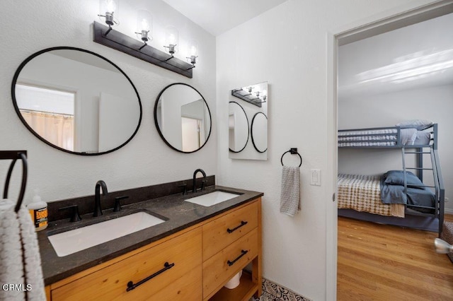 full bath featuring double vanity, wood finished floors, ensuite bathroom, and a sink