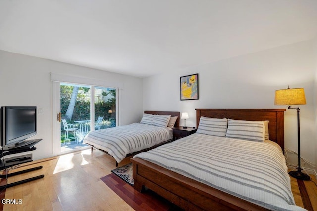 bedroom with access to exterior and wood finished floors