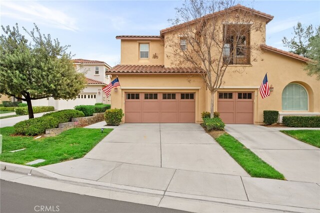 mediterranean / spanish-style house featuring a tile roof, concrete driveway, a garage, and stucco siding