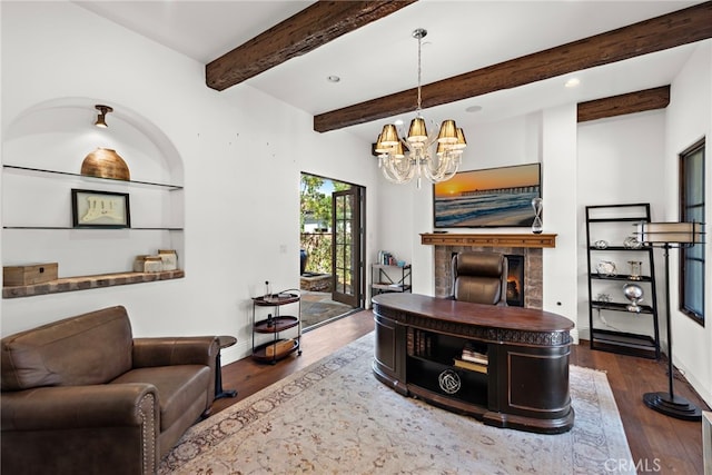 living area with beam ceiling, a warm lit fireplace, wood finished floors, baseboards, and a chandelier