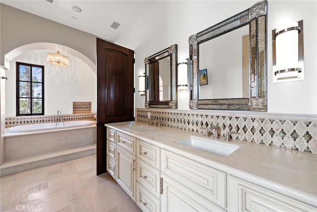 full bath with a sink, visible vents, a garden tub, and double vanity