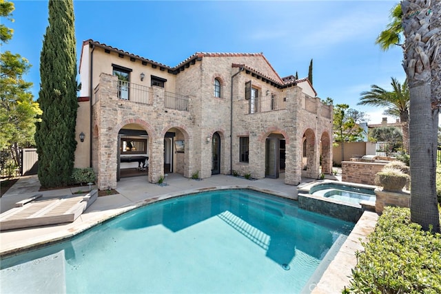 rear view of property with stone siding, a balcony, fence, and a patio area