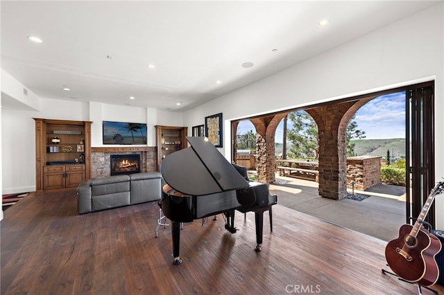 sitting room with recessed lighting, wood finished floors, baseboards, and a warm lit fireplace