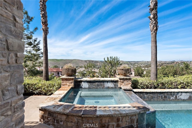 view of pool with an in ground hot tub and a mountain view