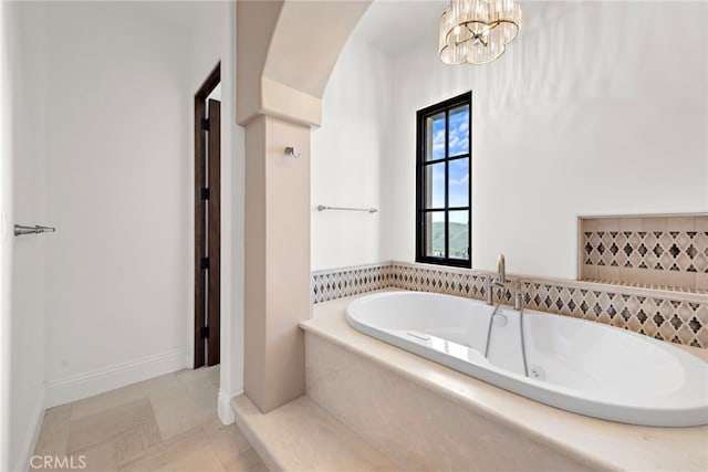 bathroom featuring a bath, baseboards, and a chandelier