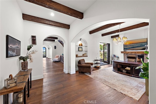 interior space with wood finished floors, baseboards, arched walkways, beamed ceiling, and a chandelier