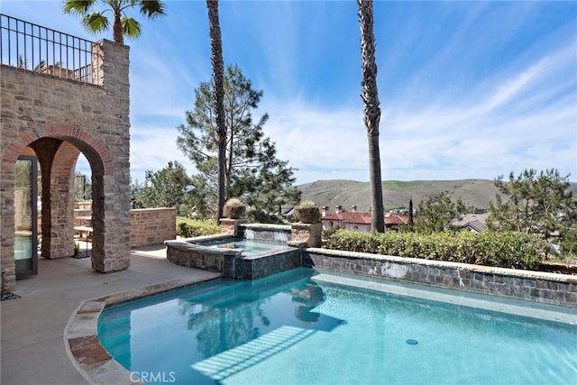 view of pool featuring a patio, a mountain view, and a pool with connected hot tub