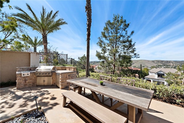 view of patio / terrace with outdoor dining space, an outdoor kitchen, a mountain view, and area for grilling