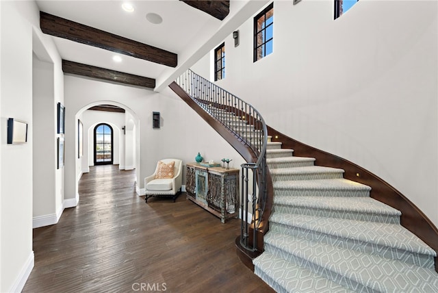 stairs with wood finished floors, baseboards, beam ceiling, recessed lighting, and arched walkways