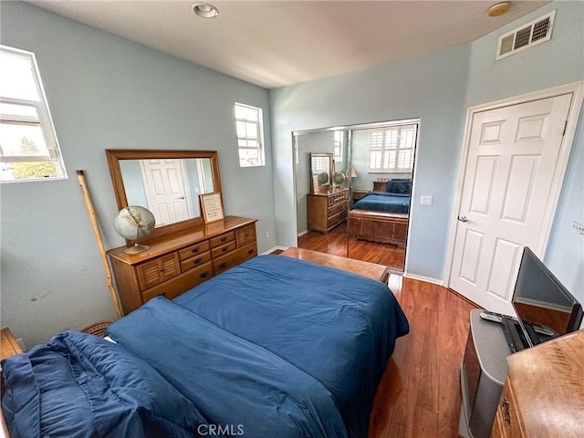 bedroom with wood finished floors, visible vents, and baseboards