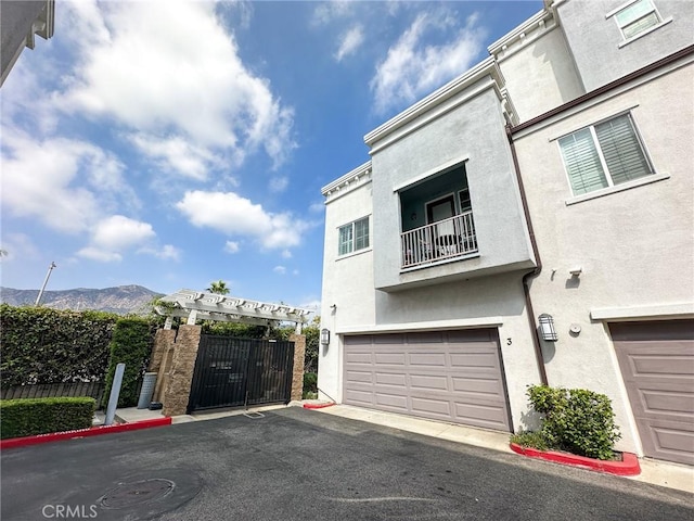 exterior space featuring a balcony, fence, an attached garage, stucco siding, and a mountain view