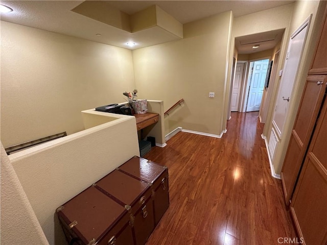 hallway with baseboards, an upstairs landing, and dark wood-style floors