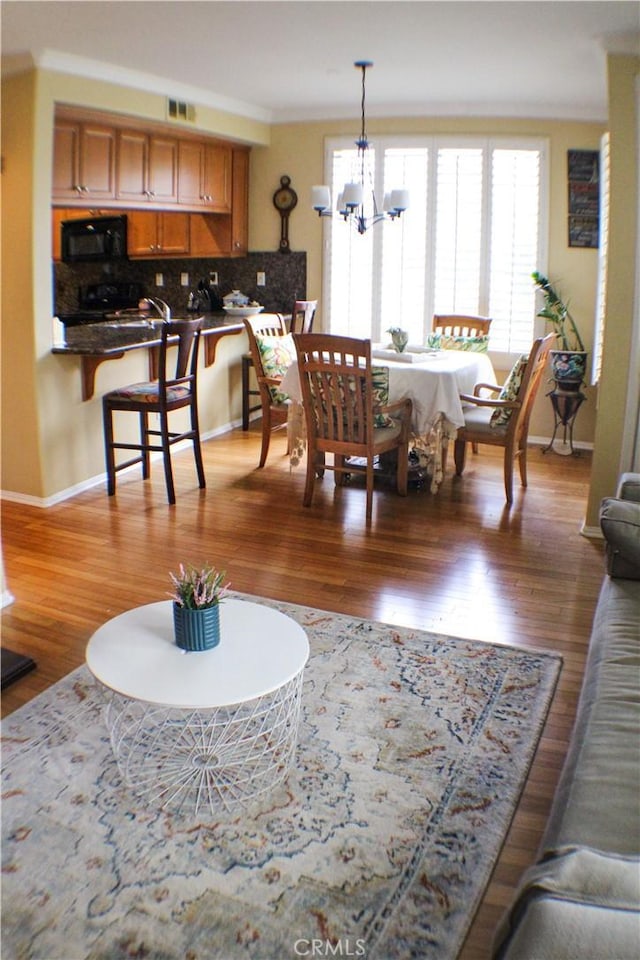 living room featuring visible vents, baseboards, an inviting chandelier, and wood finished floors