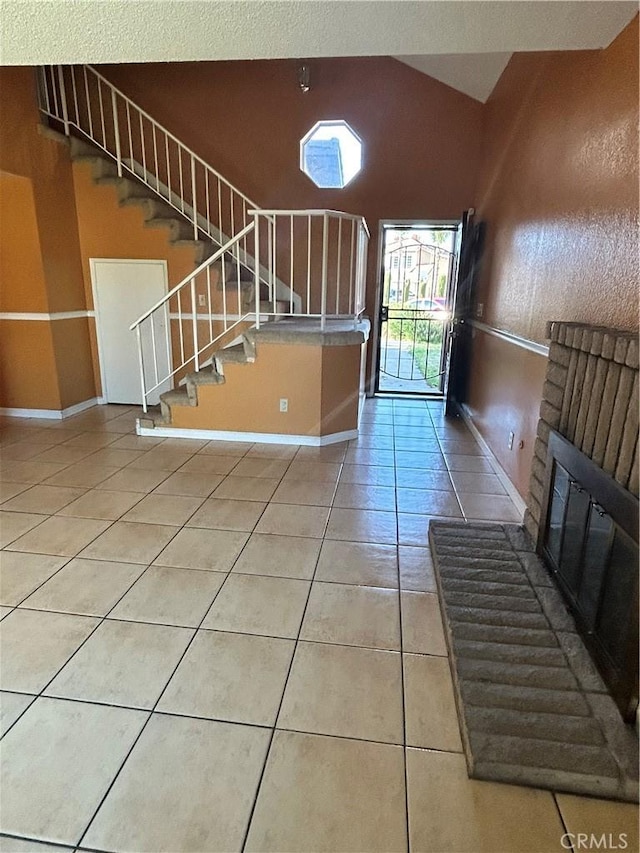 stairway featuring baseboards, a brick fireplace, vaulted ceiling, and tile patterned flooring