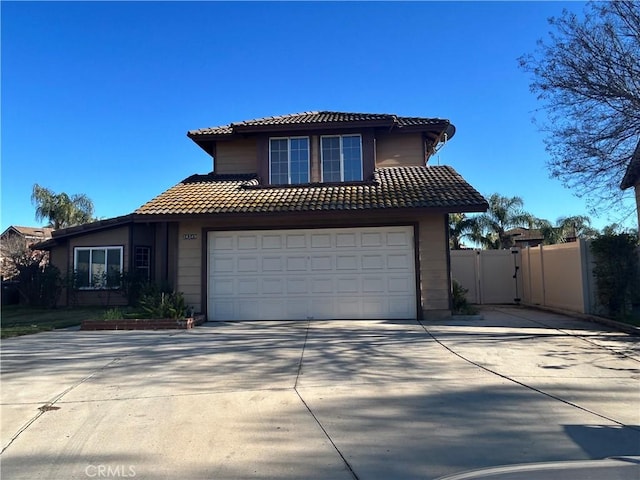 traditional-style home with a tile roof, concrete driveway, a garage, and a gate