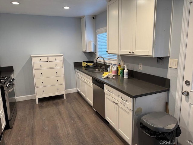 kitchen with dark wood-style floors, a sink, gas range oven, dishwasher, and dark countertops