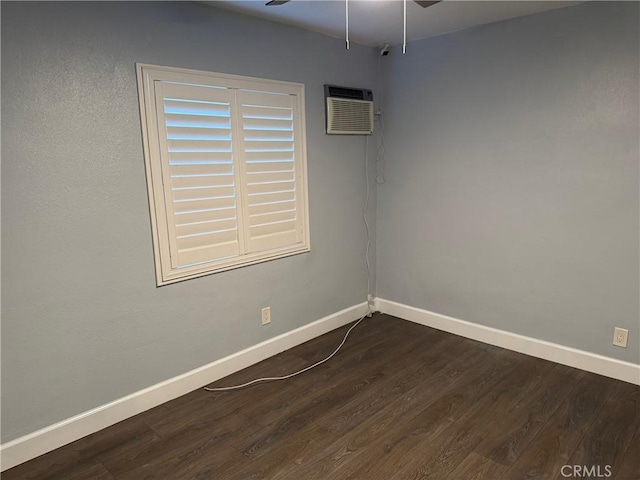 empty room featuring baseboards, dark wood-style flooring, a wall mounted air conditioner, and ceiling fan