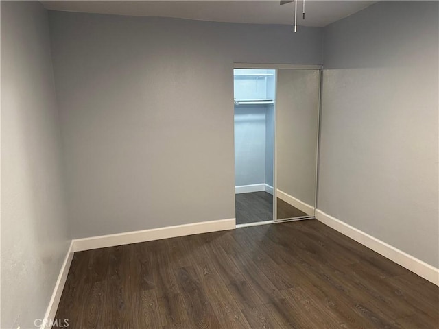 unfurnished bedroom with a closet, baseboards, and dark wood-style floors