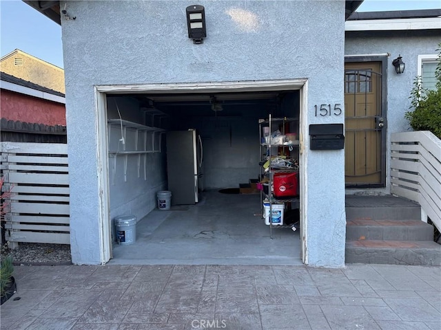 garage featuring freestanding refrigerator and fence