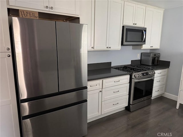 kitchen featuring stainless steel appliances, dark countertops, dark wood-style floors, and white cabinetry