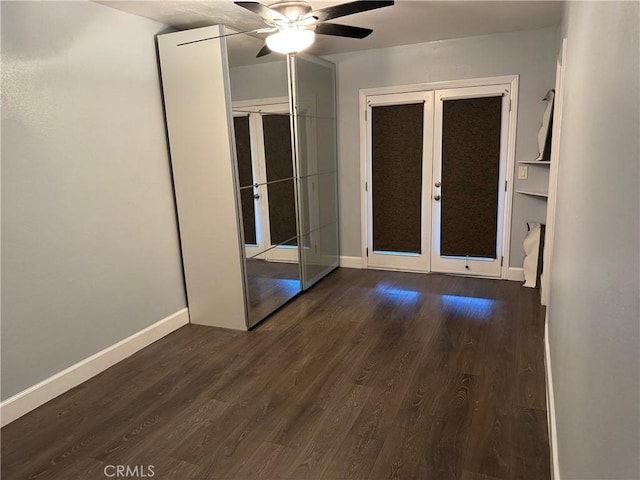 empty room featuring french doors, baseboards, and dark wood-style flooring