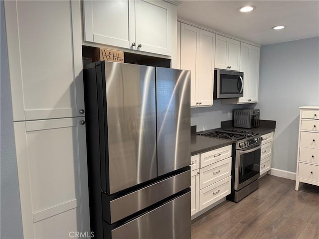 kitchen featuring white cabinetry, dark countertops, dark wood-style flooring, and appliances with stainless steel finishes