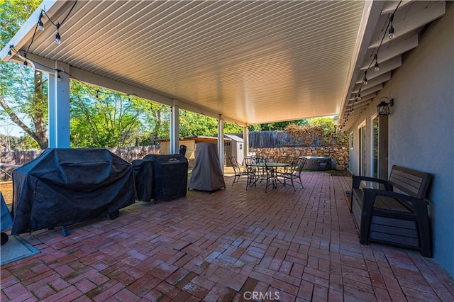 view of patio with outdoor dining area, an outdoor structure, a fenced backyard, a grill, and a storage unit