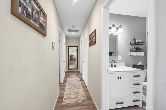 hallway with dark wood-style flooring, baseboards, and a sink