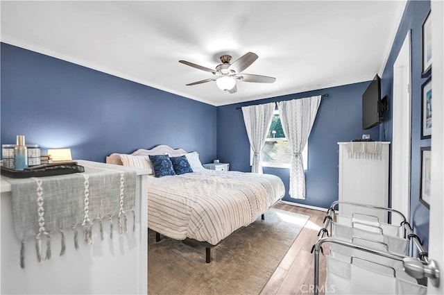 bedroom featuring ornamental molding, baseboards, ceiling fan, and wood finished floors