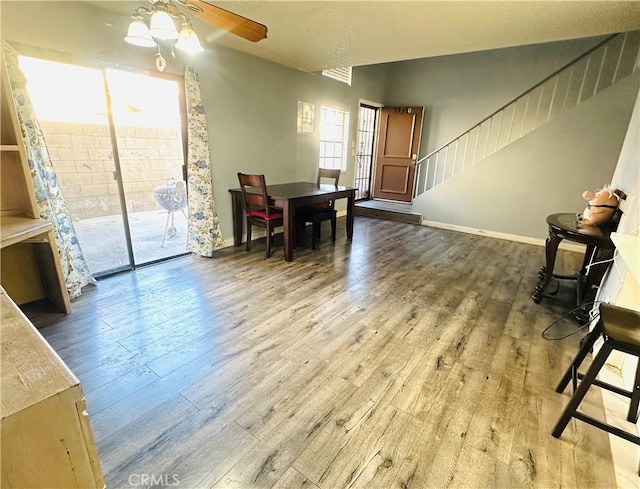 dining room featuring ceiling fan, baseboards, wood finished floors, and stairs