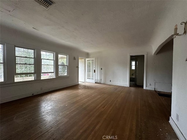 unfurnished living room featuring visible vents, a textured ceiling, and wood finished floors