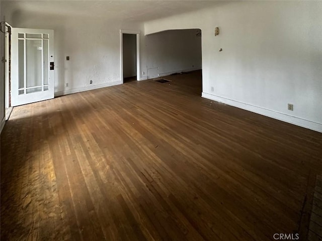 unfurnished room featuring visible vents, baseboards, and dark wood-style flooring