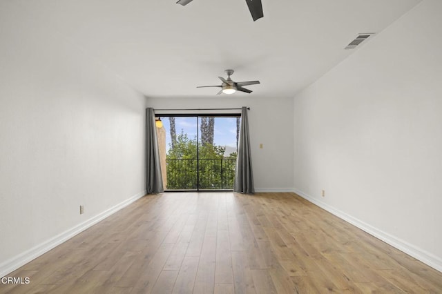 empty room with ceiling fan, visible vents, baseboards, and wood finished floors