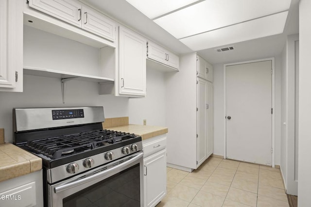 kitchen featuring tile counters, white cabinets, stainless steel range with gas stovetop, and visible vents