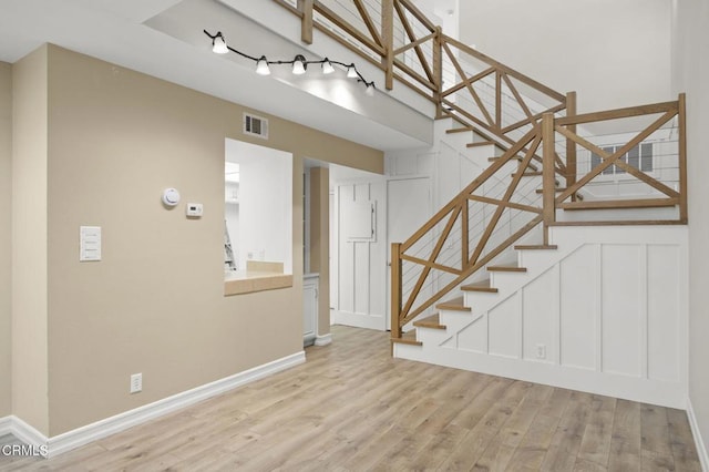 stairway with visible vents, baseboards, wood finished floors, and a decorative wall